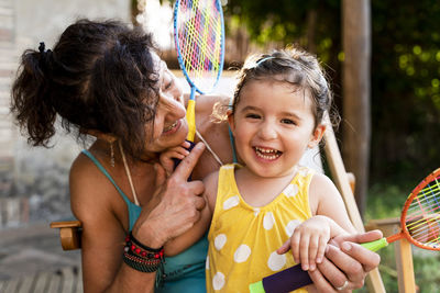 Grandmother playing with little girl and badminton rackets outdoors