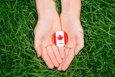 Human hands holding round badge with canadian flag symbol. canada day national celebration 