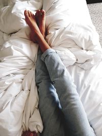 Low section of woman relaxing on bed at home