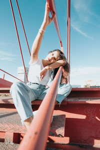 Full length of young woman sitting on railing