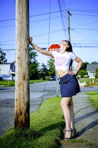 Full length of young woman standing against tree