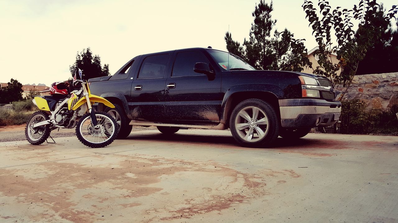 transportation, mode of transport, land vehicle, bicycle, stationary, parked, parking, car, travel, street, road, tree, riding, side view, sky, on the move, outdoors, wheel, day, cycling