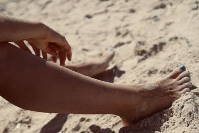 Low section of man on sand at beach