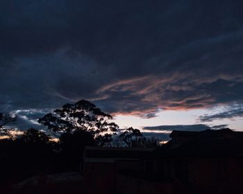 Silhouette trees and buildings against sky at sunset