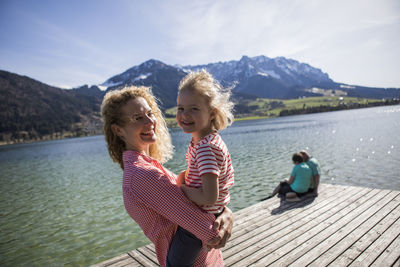 Austria, tyrol, walchsee, happy mother carrying daughter at the lake