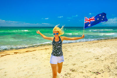 Woman holding australian flag running at beach