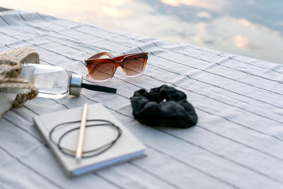 Diary and pencil, sunglasses, a bottle of water lie on the picnic blanket.