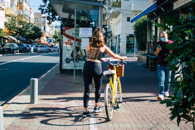 Woman riding bicycle on footpath in city