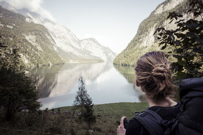 Rear view of woman looking at lake against mountains