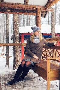 Full length of woman sitting on bench outdoors