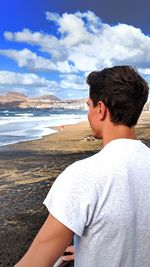 Young man on beach against sky
