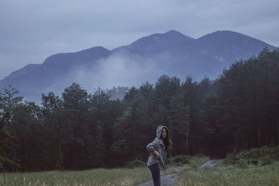 Side view of woman standing on field against mountain during dusk