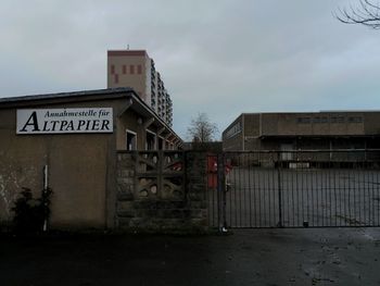 Information sign by building against sky