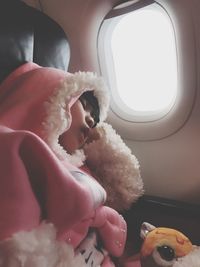 Girl wearing pink warm clothing sleeping in airplane