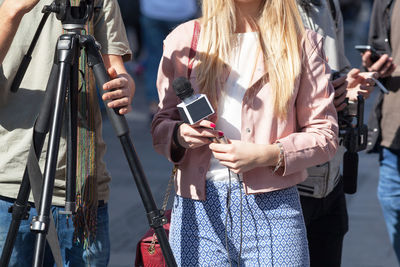 Midsection of female journalist holding microphone