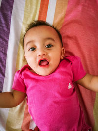 Close-up of cute baby girl lying on bed at home