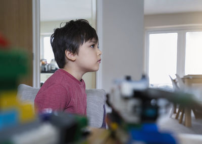 Close-up of boy looking away while standing at home