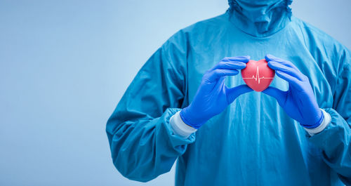 Midsection of person holding umbrella against blue background