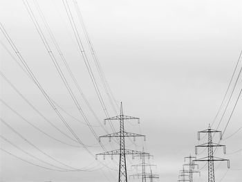 Low angle view of electricity pylon against clear sky