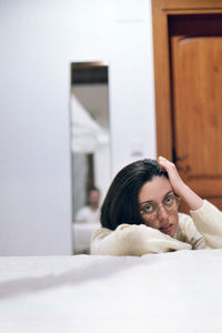 Portrait of woman lying on bed at home