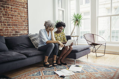 Businesswomen using tablet computer on sofa in creative office