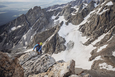 A rock climber seems tiny against the backdrop of massive mountains