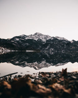 Scenic view of lake by snowcapped mountain against clear sky