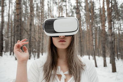 Woman wearing virtual reality simulator against trees outdoors