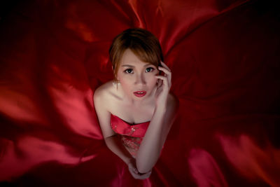 Portrait of beautiful young woman lying on bed