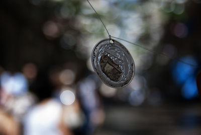 Close-up of flattened bottle cap suspended by string