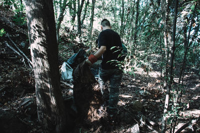 Full length of man standing amidst trees in forest