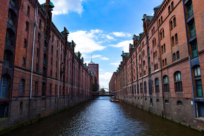 Canal amidst buildings in city against sky