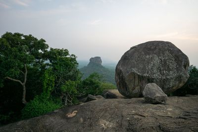 Rock formations by trees against sky