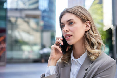 Portrait of young woman looking away while standing outdoors