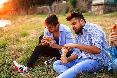 Friends using mobile phone while sitting on field