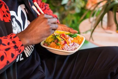 Midsection of man holding a bowl of vegetables 