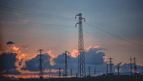 Low angle view of silhouette electricity pylon against sky during sunset