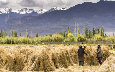 Rear view of people walking on field against mountains