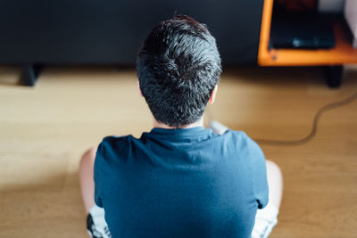 Rear view of man sitting on table at home