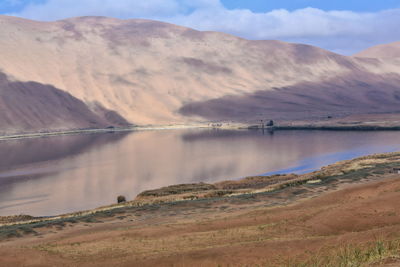 1152 sumu barun jaran lake in badain jaran desert-dark water reflecting cloudy sky and dunes. china.