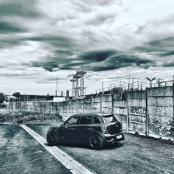 Cars on road against cloudy sky