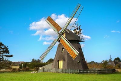 Traditional windmill on field against sky