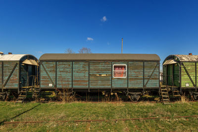 Abandoned train on field against blue sky
