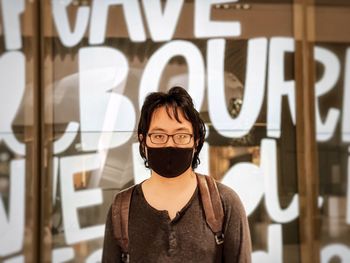 Portrait of young woman standing against wall