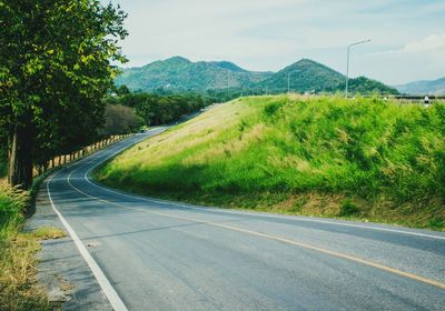 Scenic view of road by mountains against sky