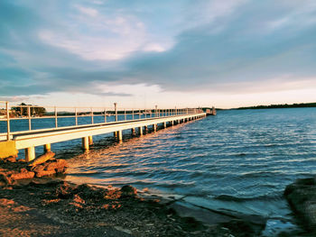 Pier over sea against sky during sunset