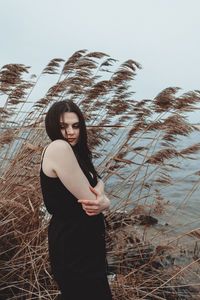 Young woman looking away while standing on land against sky