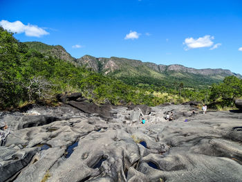 Women on rock formation against blue sky