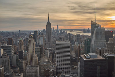 Modern buildings in city against sky during sunset