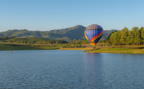 Hot air balloon flying over mountain against clear sky